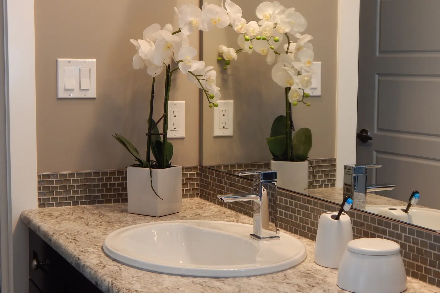 A remodeled bathroom vanity with a tiled backsplash