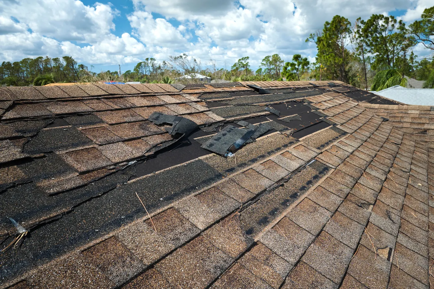 Storm-damaged asphalt shingles on a house roof