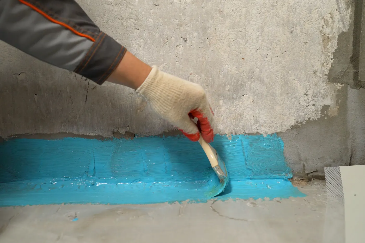 Waterproofing tape applied where a basement wall meets the floor