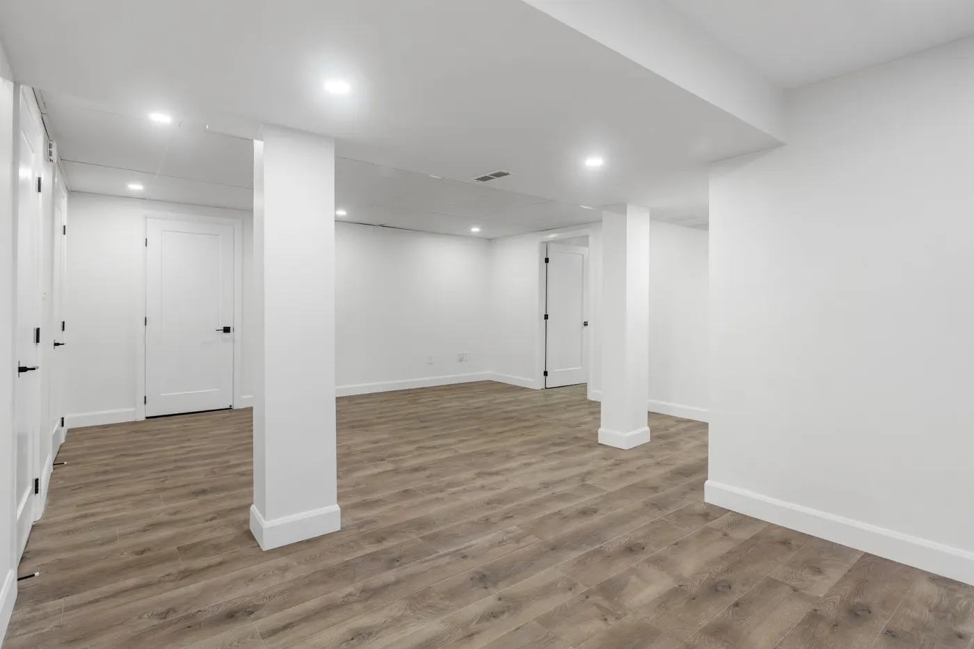 A finished basement with wood-look flooring and white walls