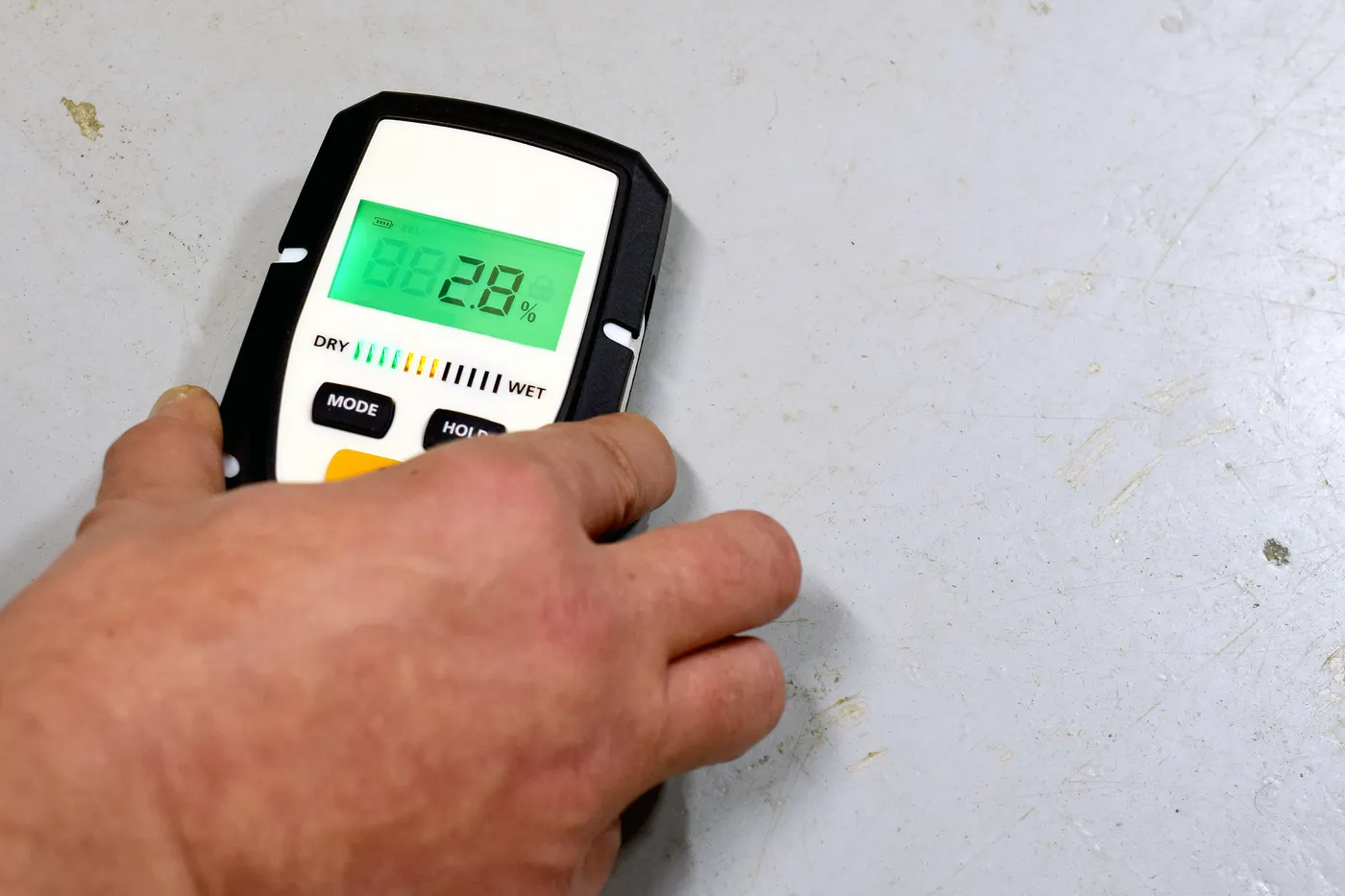 A moisture meter being used on a basement wall