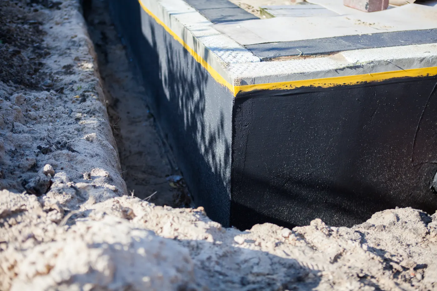 A waterproofing membrane applied to a foundation wall in an open trench