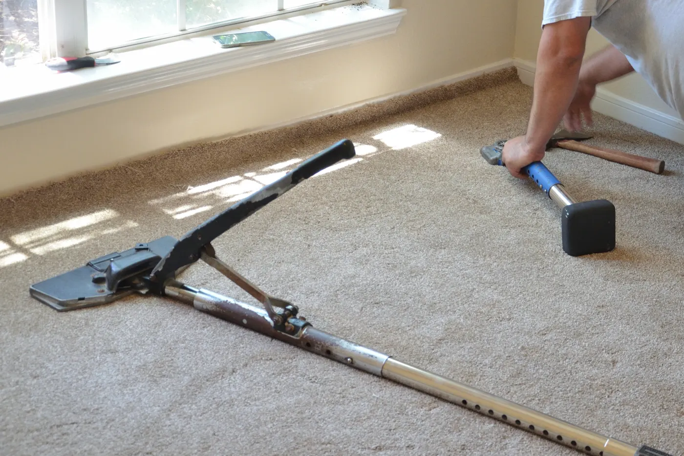 An installer stretching new carpet into place