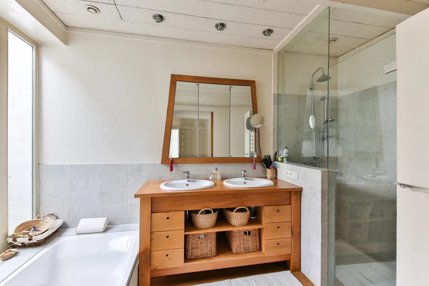A remodeled bathroom with a wood double vanity and a glass shower