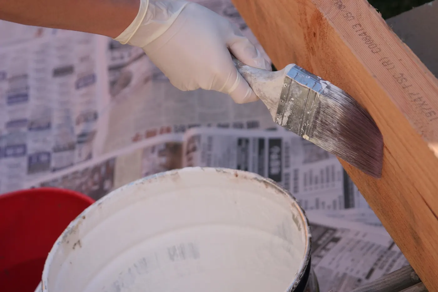 A brush painting wood trim beside an open paint can