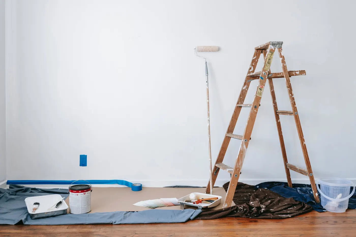 A room prepared for painting with drop cloths, a ladder and paint